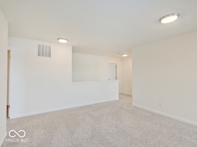 empty room featuring visible vents, light carpet, and baseboards