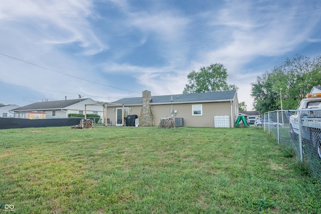 rear view of property featuring a lawn and central AC