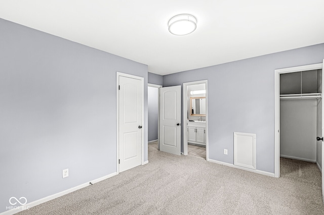 unfurnished bedroom featuring ensuite bath, sink, light colored carpet, and a closet