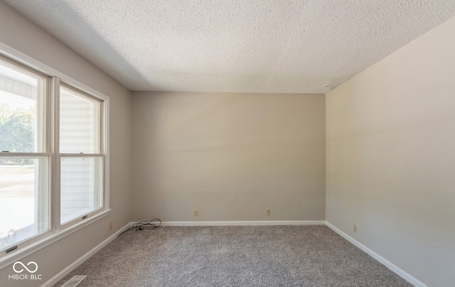 carpeted empty room with a textured ceiling