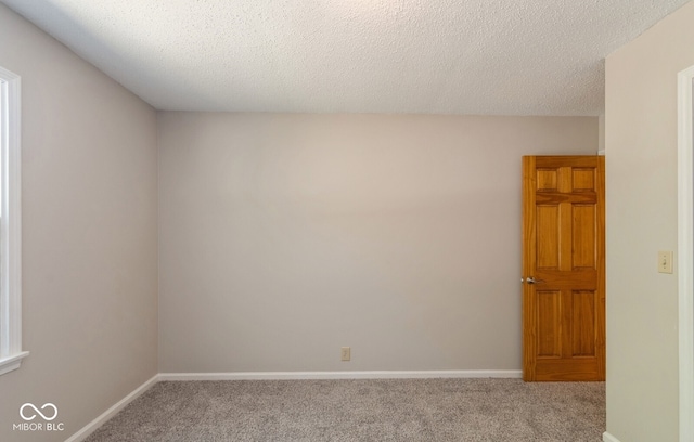 carpeted empty room featuring a textured ceiling