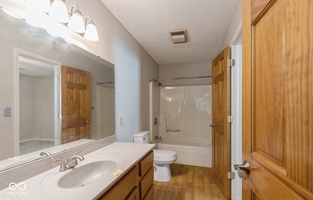 full bathroom featuring vanity, a textured ceiling, shower / bathing tub combination, hardwood / wood-style flooring, and toilet