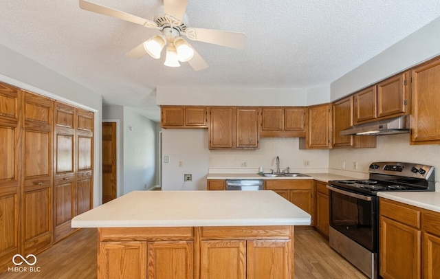 kitchen with ceiling fan, a kitchen island, stainless steel appliances, and light hardwood / wood-style flooring