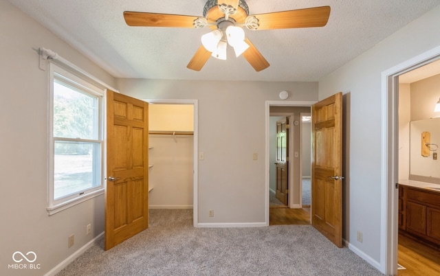 unfurnished bedroom featuring ceiling fan, a textured ceiling, a closet, and light carpet