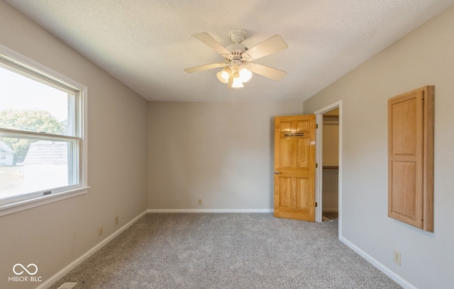 unfurnished bedroom with ceiling fan, light colored carpet, and a textured ceiling