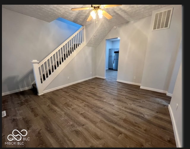 unfurnished living room with a textured ceiling, dark hardwood / wood-style floors, and ceiling fan