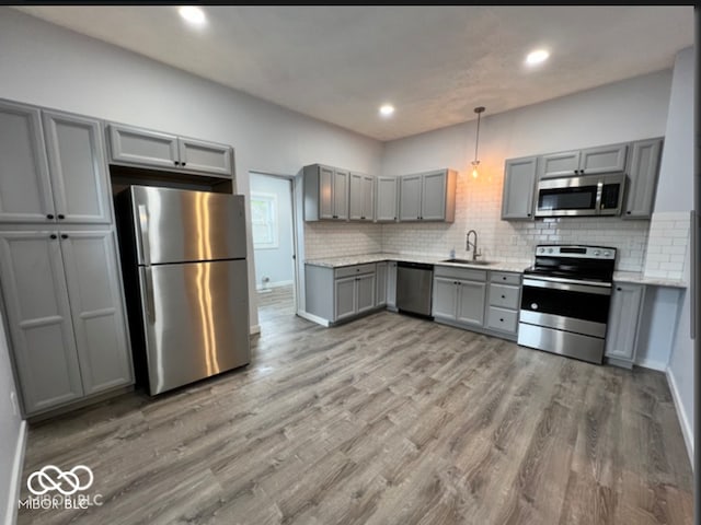 kitchen with sink, decorative light fixtures, light hardwood / wood-style flooring, gray cabinets, and appliances with stainless steel finishes