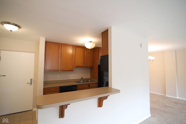 kitchen with light tile patterned floors, sink, kitchen peninsula, black appliances, and a kitchen bar