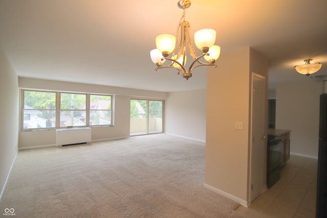 empty room featuring radiator, a notable chandelier, carpet, and a wealth of natural light