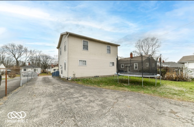 rear view of property featuring a trampoline, an outdoor structure, and a garage