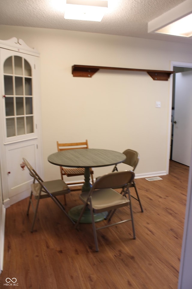 dining space with wood-type flooring and a textured ceiling