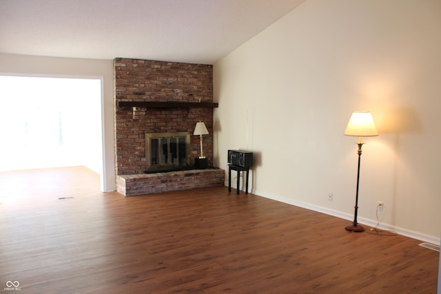 unfurnished living room featuring vaulted ceiling, a fireplace, and dark hardwood / wood-style flooring