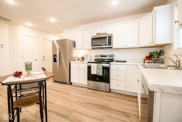 kitchen with white cabinets, appliances with stainless steel finishes, light hardwood / wood-style flooring, and sink