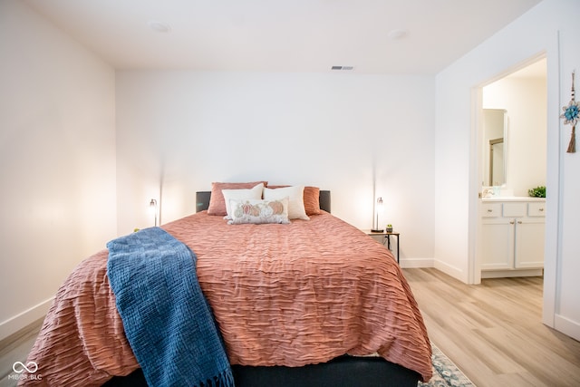 bedroom with light hardwood / wood-style floors and connected bathroom