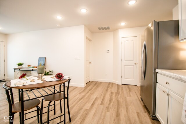 kitchen featuring white cabinets, stainless steel fridge, and light hardwood / wood-style floors