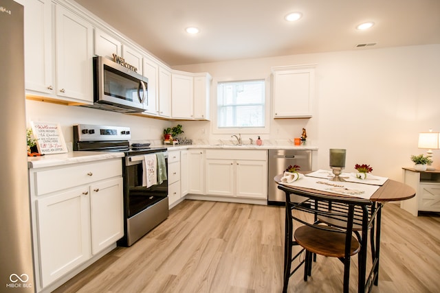 kitchen featuring sink, light hardwood / wood-style flooring, white cabinets, and appliances with stainless steel finishes