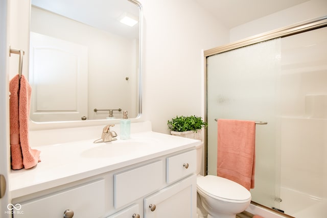 bathroom featuring vanity, toilet, and a shower with shower door