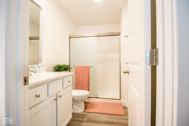 bathroom featuring vanity, toilet, wood-type flooring, and a shower with door