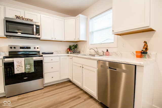 kitchen with white cabinetry, sink, light hardwood / wood-style flooring, and appliances with stainless steel finishes