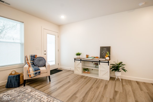 living area with light wood-type flooring and a healthy amount of sunlight