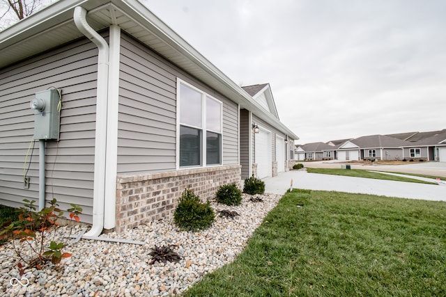 view of side of property featuring a garage and a lawn