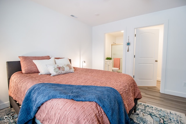 bedroom featuring hardwood / wood-style flooring and ensuite bath