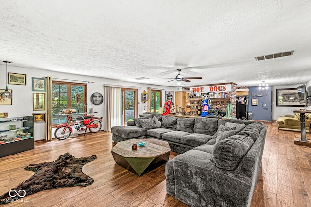 living room featuring ceiling fan, a textured ceiling, and light hardwood / wood-style flooring