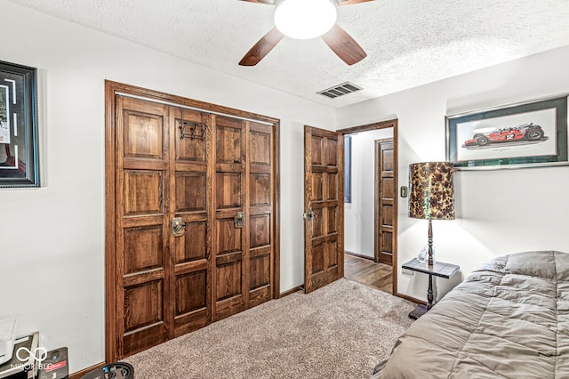 carpeted bedroom with ceiling fan and a textured ceiling