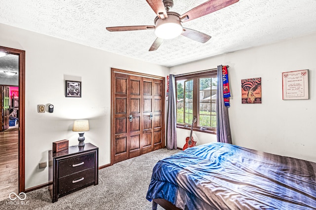 bedroom with a textured ceiling, carpet, ceiling fan, and a closet