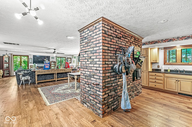 kitchen with ceiling fan, brick wall, a textured ceiling, and light hardwood / wood-style floors