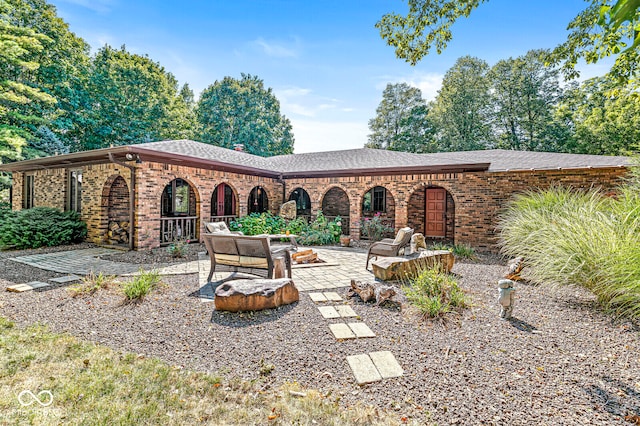 rear view of house with a fire pit and a patio