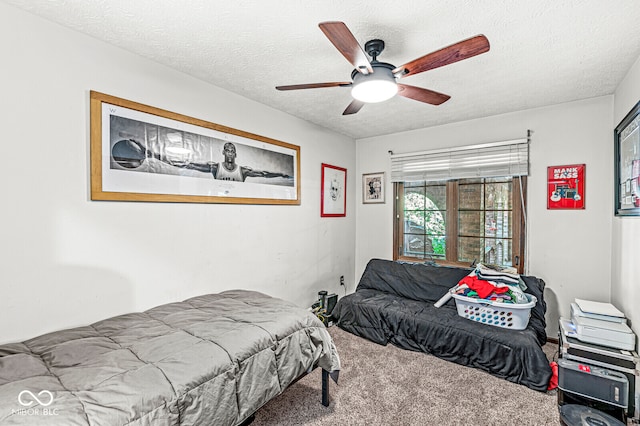 bedroom with ceiling fan, carpet floors, and a textured ceiling