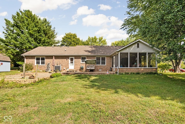 rear view of house featuring a patio, a sunroom, a yard, and central air condition unit