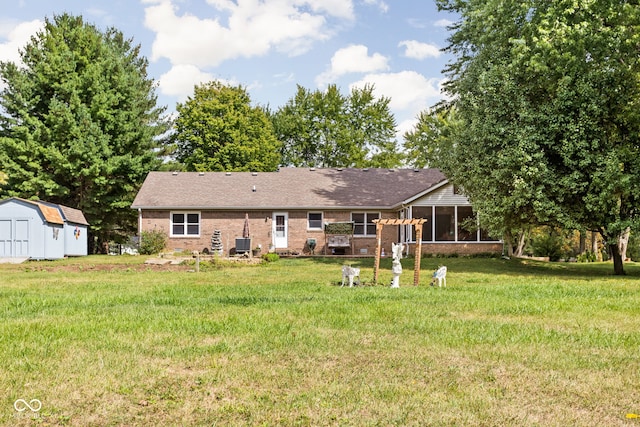 rear view of property with cooling unit, a yard, and a storage unit