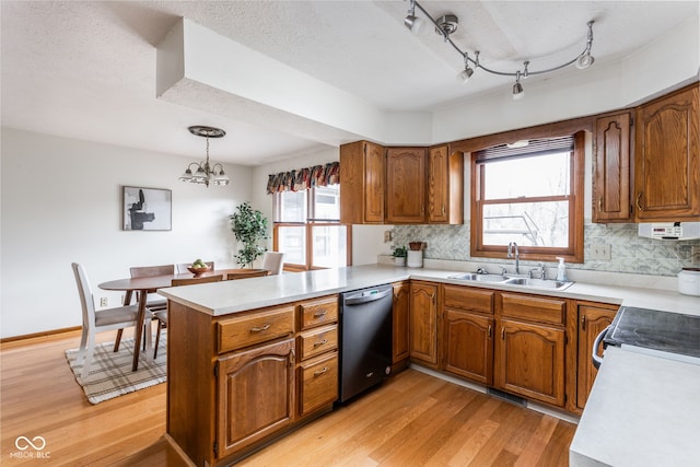 kitchen featuring sink, appliances with stainless steel finishes, kitchen peninsula, pendant lighting, and light hardwood / wood-style floors