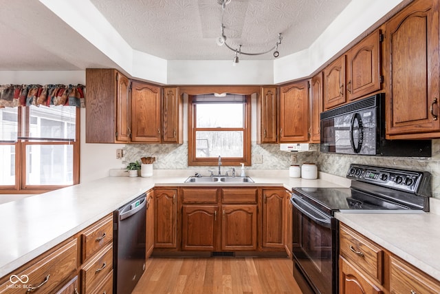 kitchen with tasteful backsplash, light hardwood / wood-style floors, sink, and black appliances