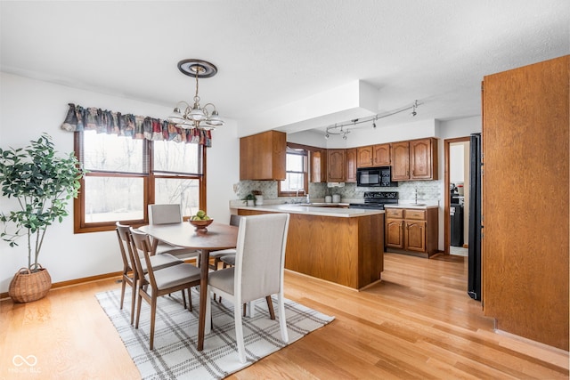 dining area featuring an inviting chandelier, sink, light hardwood / wood-style flooring, and a textured ceiling