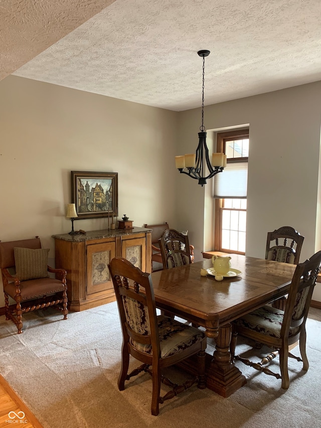 carpeted dining room featuring an inviting chandelier and a textured ceiling