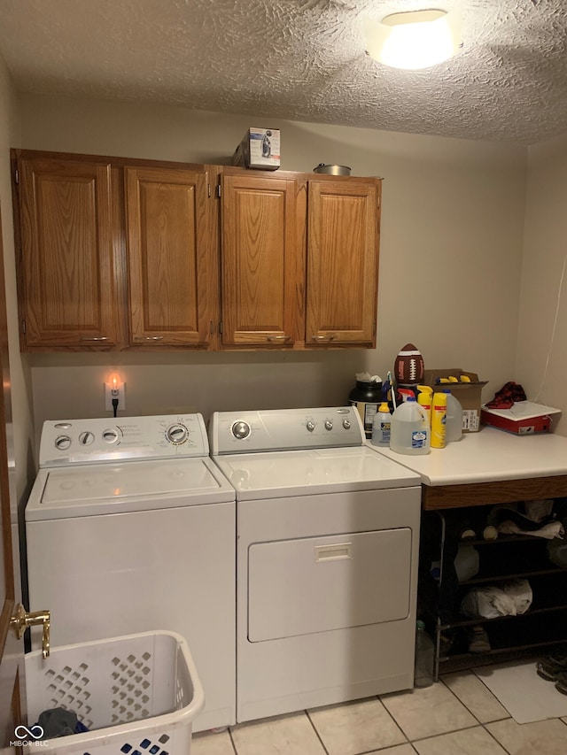 laundry area with cabinets, separate washer and dryer, light tile patterned floors, and a textured ceiling