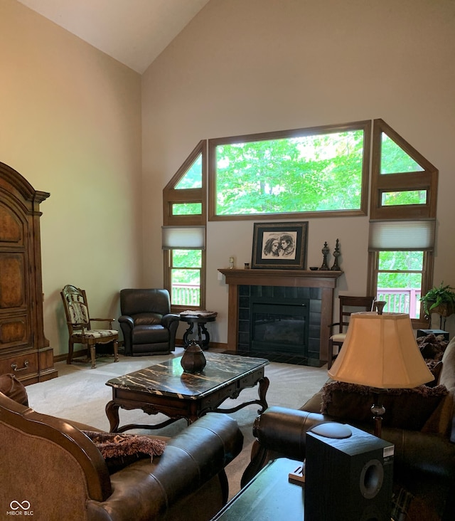 living room featuring light colored carpet, a healthy amount of sunlight, a tiled fireplace, and vaulted ceiling