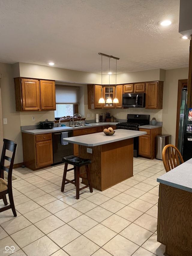 kitchen featuring pendant lighting, sink, a kitchen breakfast bar, a center island, and black appliances