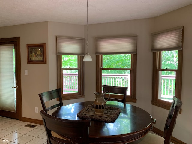 dining area with a textured ceiling and light tile patterned flooring