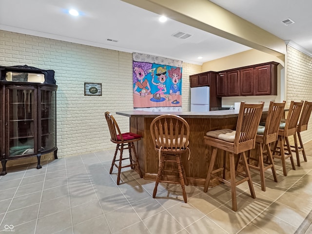 bar featuring light tile patterned floors, brick wall, and white fridge