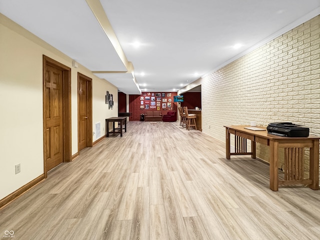 interior space with brick wall and light hardwood / wood-style flooring