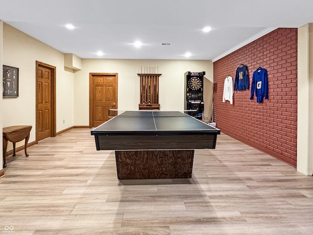 recreation room featuring brick wall and light hardwood / wood-style floors