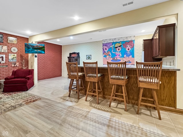 bar with light hardwood / wood-style floors and brick wall