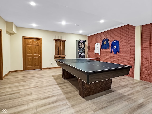 recreation room featuring light wood-type flooring and brick wall