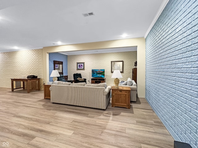 living room with brick wall and light hardwood / wood-style flooring