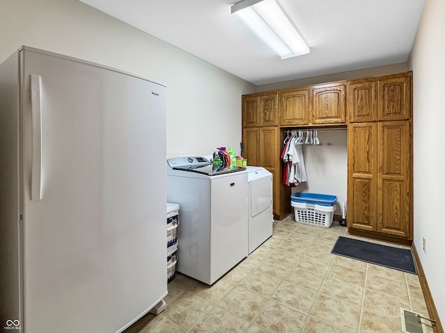 clothes washing area with cabinets and washer and dryer