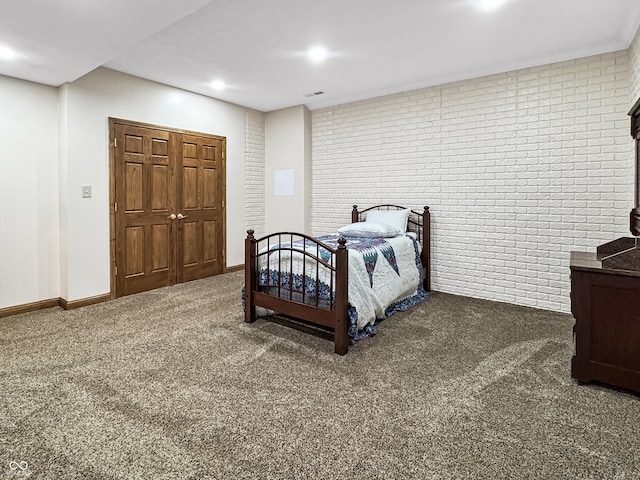 carpeted bedroom featuring brick wall and a closet